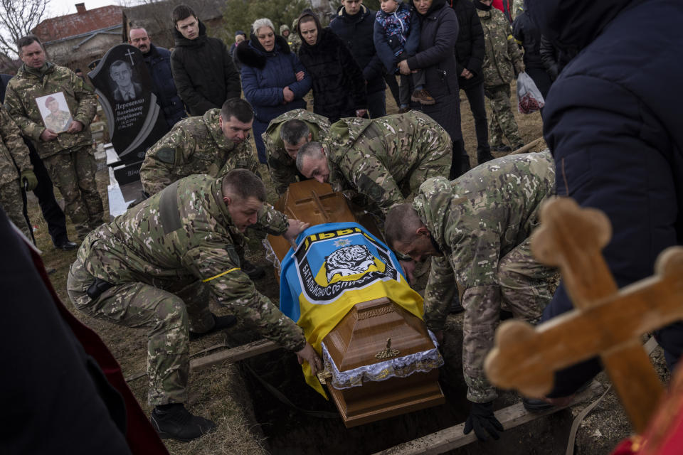 The coffin of senior police sergeant Roman Rushchyshyn is lowered during his funeral in the village of Soposhyn, outskirts of Lviv, western Ukraine, Thursday, March 10, 2022, in Lviv. Rushchyshyn, a member of the Lviv Special Police Patrol Battalion, was killed in the Luhansk Region. (AP Photo/Bernat Armangue)