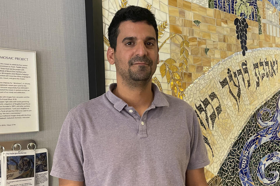 Shai Avny stands in front of a mosaic in Mount Zion Temple in St. Paul, Minn., on Friday, June 21, 2023, after watching dozens of people become U.S. citizens at a naturalization ceremony. Avny said he immigrated from Israel five years ago, passed the U.S. citizenship test last year and became a U.S. citizen shortly after. The citizenship test is being updated and some immigrants, including Avny, worry the changes will hurt test-takers with lower levels of English proficiency. (AP Photo/Trisha Ahmed)