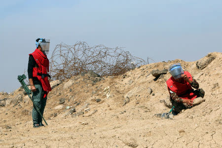 A demining team works near the village of Bitr, which in Arabic means "amputation", in Shalamjah district, east of Basra, Iraq March 4, 2018. REUTERS/Essam Al-Sudani/Files