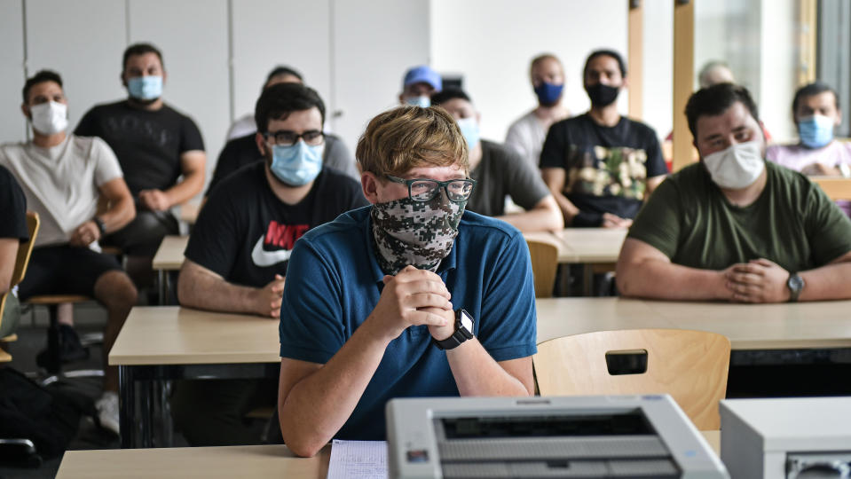 FILE - In this Thursday, Aug. 13, 2020 file photo, students of the Robert-Koch vocational college sit with face masks in the classroom during computer science lessons in Dortmund, Germany. Despite a spike in coronavirus infections, authorities in Europe are determined to send children back to school. At least 41 of Berlin’s 825 schools reported virus cases as classes resumed this month, and thousands of students have been quarantined around the country. But Germany is determined not to close schools anew, so they're sending individual students or classes into quarantine instead. (AP Photo/Martin Meissner, File)