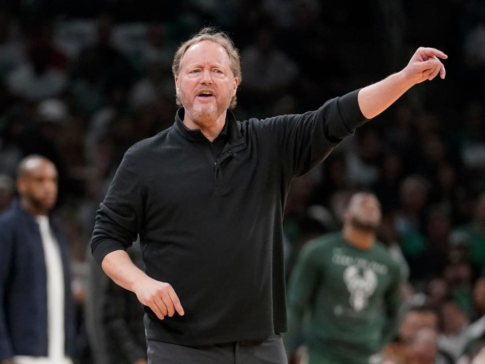 Mike Budenholzer sticks his hand out and frowns during a Bucks game.