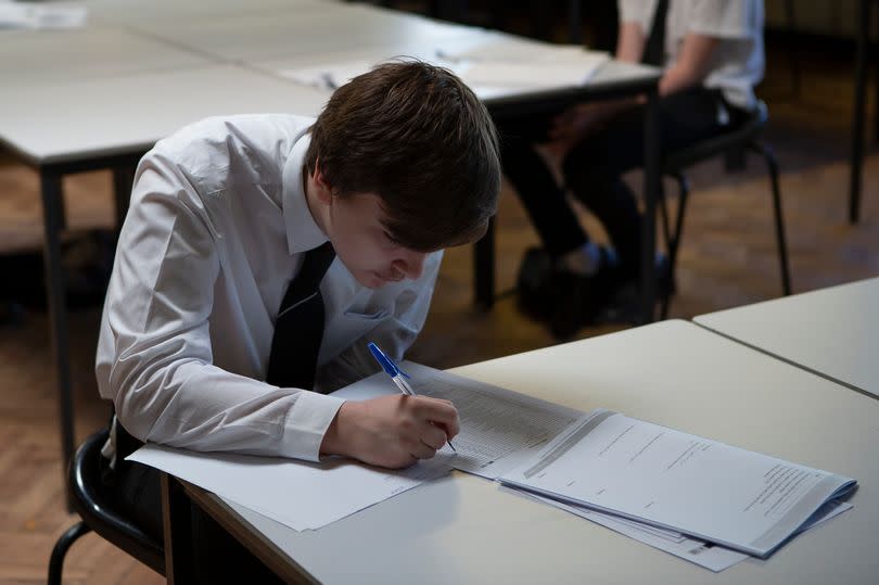 A year 10 pupil writing in an exam room