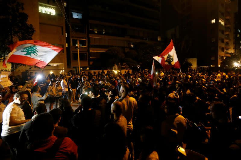 Demonstrators hold Lebanese flags as they protest outside the house of former Lebanese prime minister Fouad Siniora in Beirut