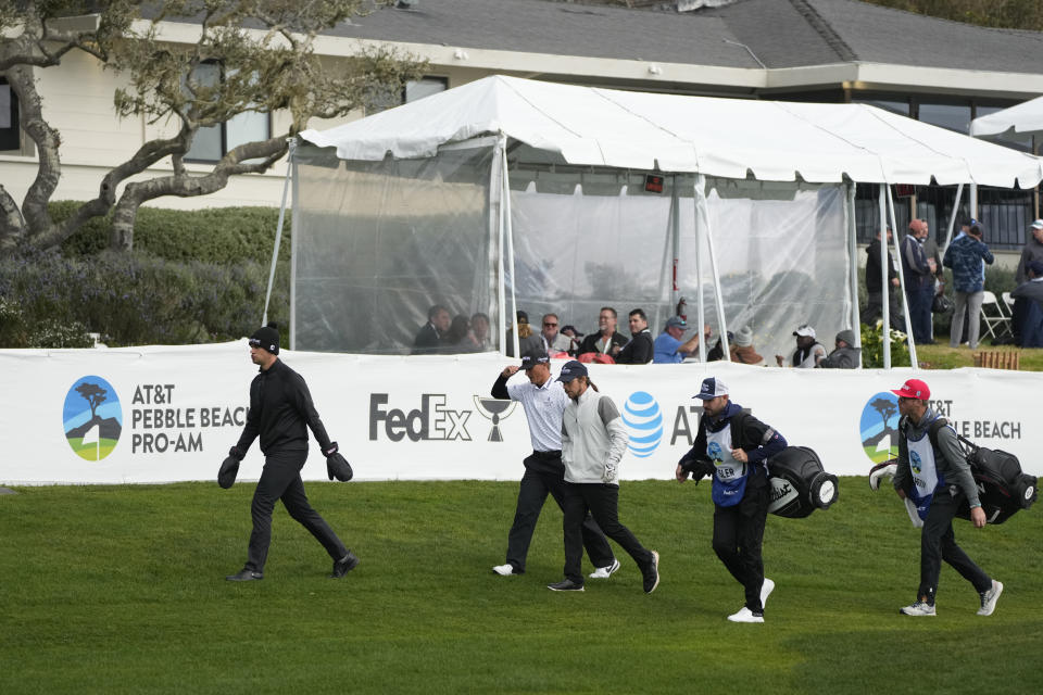 From left, the playing group of Beau Hossler, Max McGreevy and Lukas Nelson walk toward the 14th fairway of the Pebble Beach Golf Links during the second round of the AT&T Pebble Beach Pro-Am golf tournament in Pebble Beach, Calif., Friday, Feb. 3, 2023. A caddie for one of the amateurs in the group collapsed on the 11th fairway and was rushed to the hospital. (AP Photo/Eric Risberg)