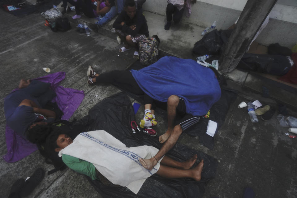 Migrants, mostly from Central America, sleep-in on the street in Huixtla, Chiapas state, Mexico, at sunrise Tuesday, Oct. 26, 2021, as they use the day to rest during their trek by foot toward the U.S. (AP Photo/Marco Ugarte)