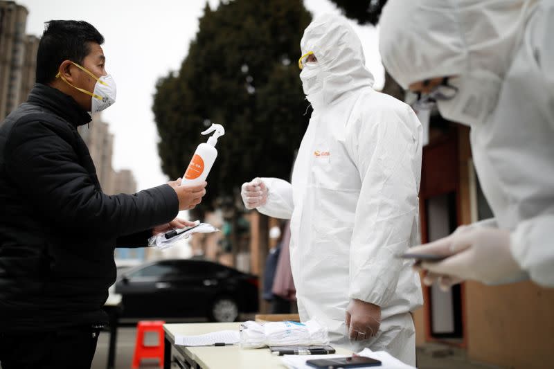 Driver receives a sprayer from staff members in protective suits at a service centre of car-hailing service Didi Chuxing in Beijing