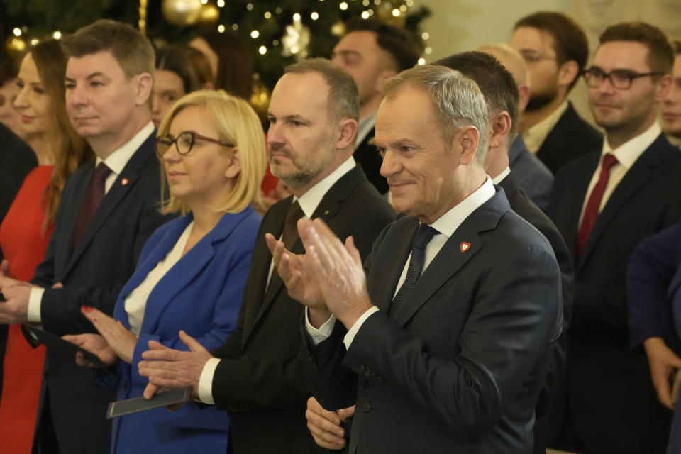 Poland's new Prime Minister Donald Tusk, right, applauds during the swearing-in ceremony at the presidential palace in Warsaw, Poland, Wednesday, Dec. 13, 2023. Donald Tusk was sworn in by the president in a ceremony where each of his ministers was also taking the oath of office. (AP Photo/Czarek Sokolowski)