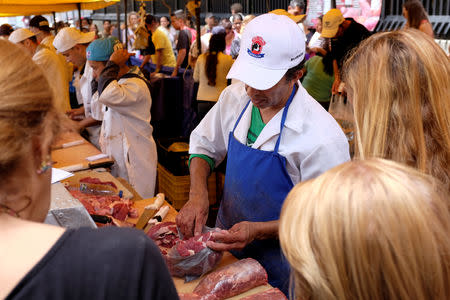 A man checks meat at a butchery stall in a street market in Caracas, Venezuela August 18, 2018. REUTERS/Marco Bello