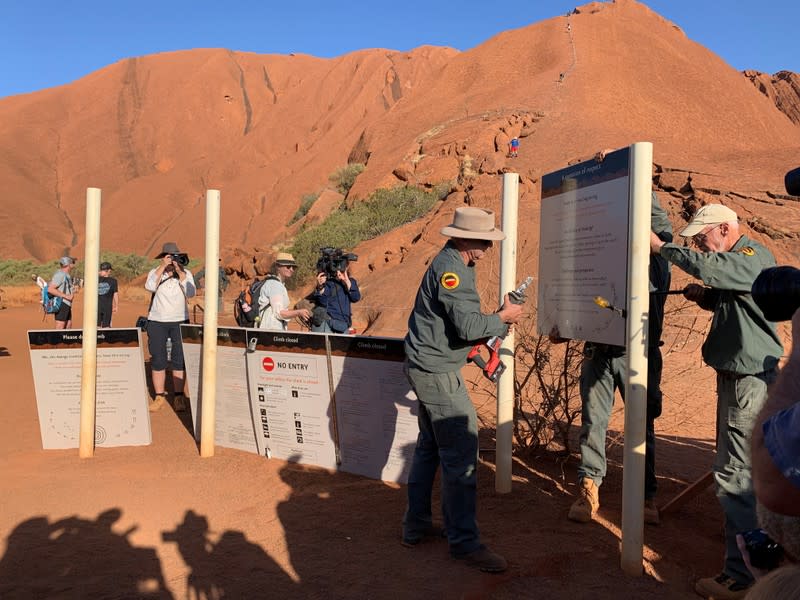 Park rangers at Uluru, formerly known as Ayers Rock, remove the old signs that explain the climb to tourists, near Yulara