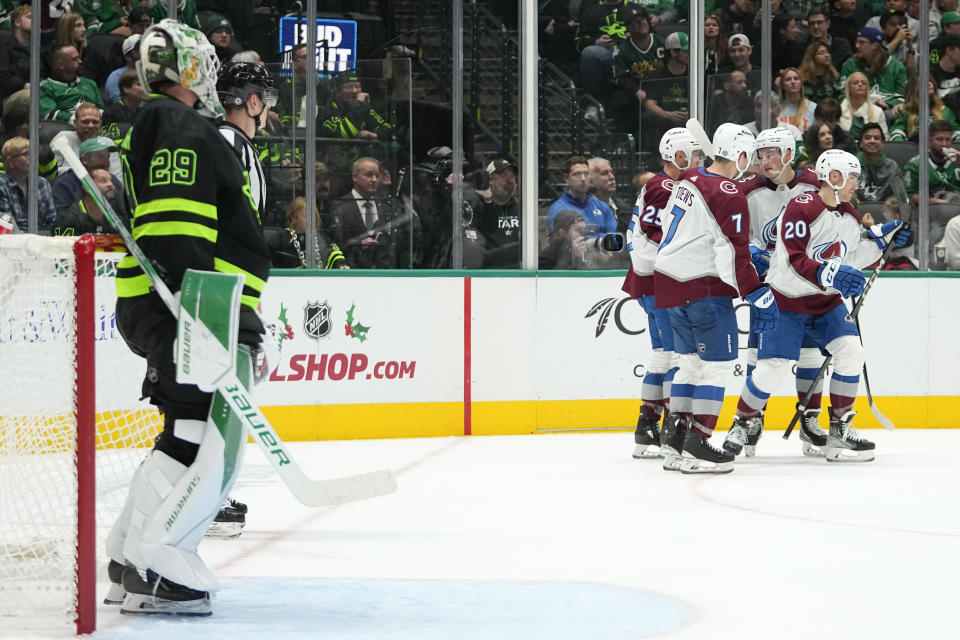 Dallas Stars goaltender Jake Oettinger, left, looks on as Colorado Avalanche players celebrate a goal by Miles Wood, not visible, during the second period of an NHL hockey game, Saturday, Nov. 18, 2023, in Dallas. (AP Photo/Julio Cortez)