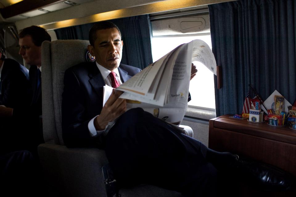President Barack Obama reads a morning newspaper aboard Marine One
