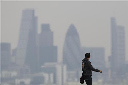 A man walks through Greenwich Park as a haze of pollution sits over the London skyline April 3, 2014. REUTERS/Luke MacGregor