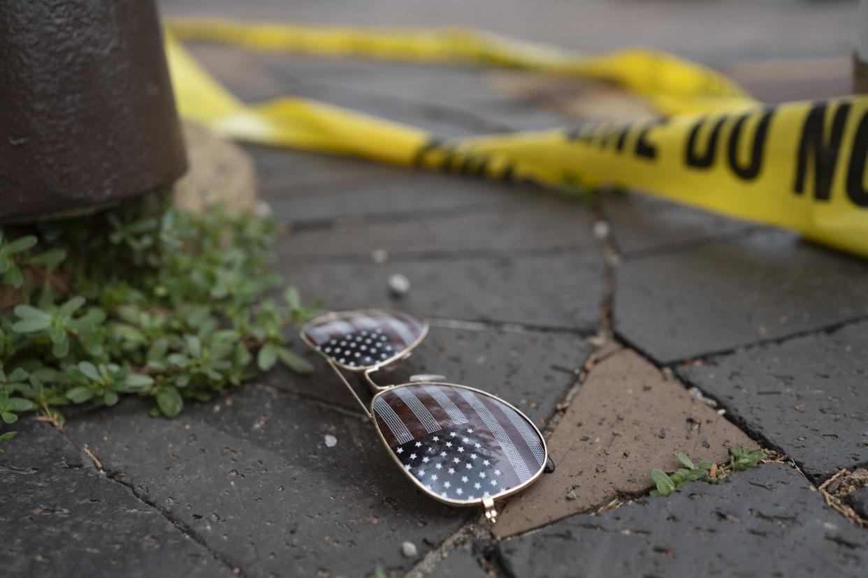 Police crime tape is seen near a pair of American flag-themed sunglasses laying on the ground at the scene of the Fourth of July parade shooting in Highland Park, Ill.