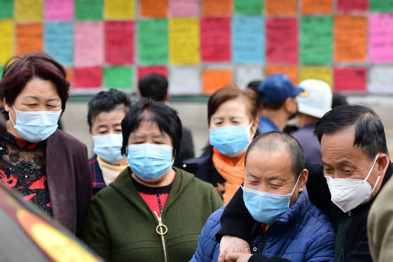 People wearing face masks look at job advertisements in Qingdao