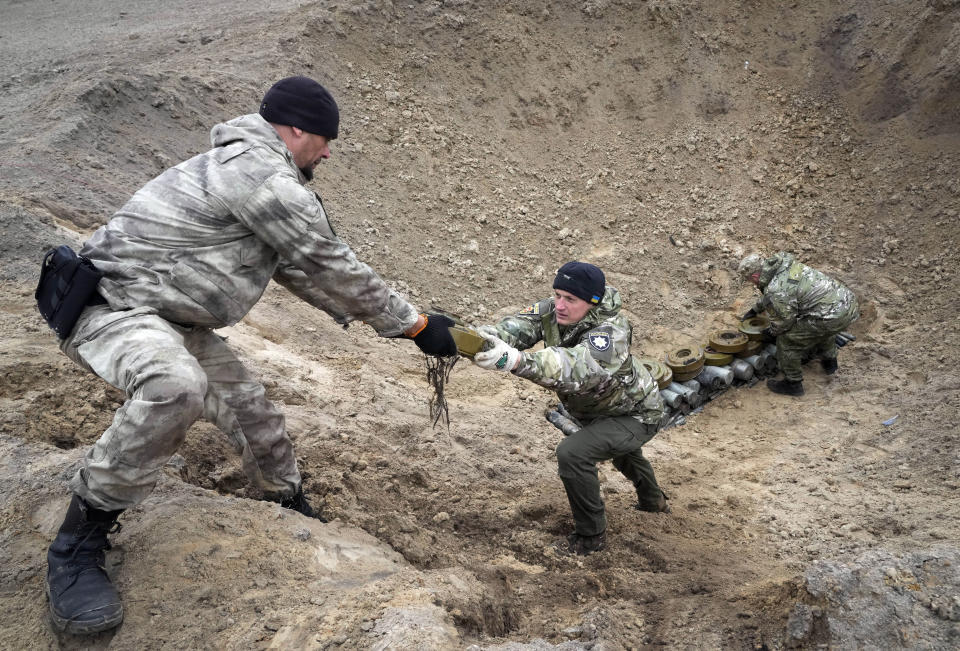 Interior ministry sappers collect explosives in a hole to detonate them near a minefield, after recent battles at the village of Moshchun close to Kyiv, Ukraine, Tuesday, April 19, 2022. (AP Photo/Efrem Lukatsky)