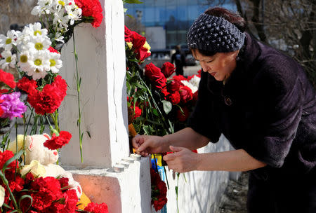 A woman lights a candle at a makeshift memorial to the victims of a recent incident, which involved an Aeroflot Sukhoi Superjet 100 passenger plane during a flight from Moscow to Murmansk, in central Murmansk, Russia May 6, 2019. REUTERS/Stringer