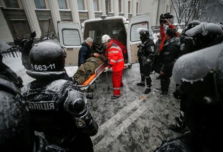A wounded protester is rushed to an ambulance as riot police look on, near the parliament building in Kiev, Ukraine March 3, 2018. REUTERS/Gleb Garanich
