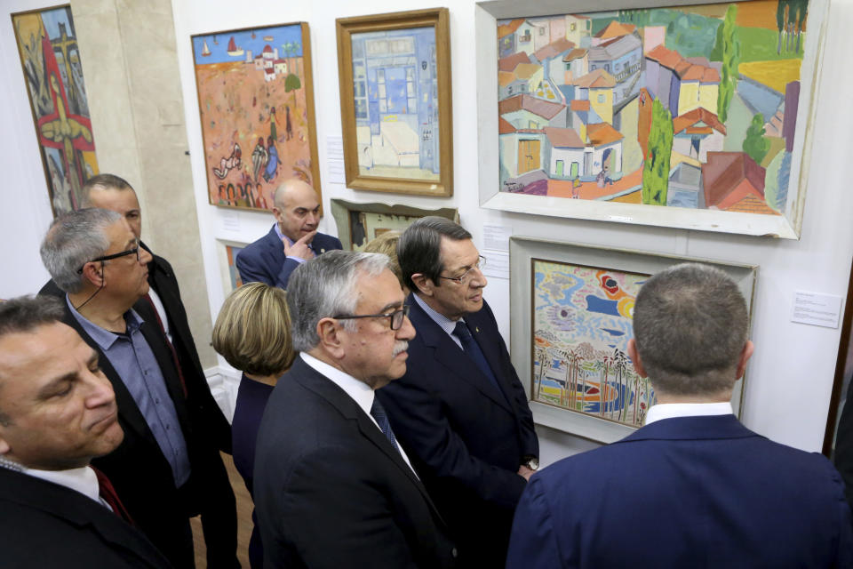 Cyprus' President Nicos Anastasiades, center right, and Mustafa Akinci, center, the leader of the ethnically divided island's breakaway Turkish Cypriots, attend an exhibition and audio visual recordings of culturally significant paintings that were recently exchanged as part of an effort to boost confidence between the ethnically divided island nation's two communities, at the Ledra Palace Hotel inside the UN controlled buffer zone in divided capital Nicosia, Cyprus, Monday, Feb. 3, 2020. (AP Photo/Petros Karadjias)