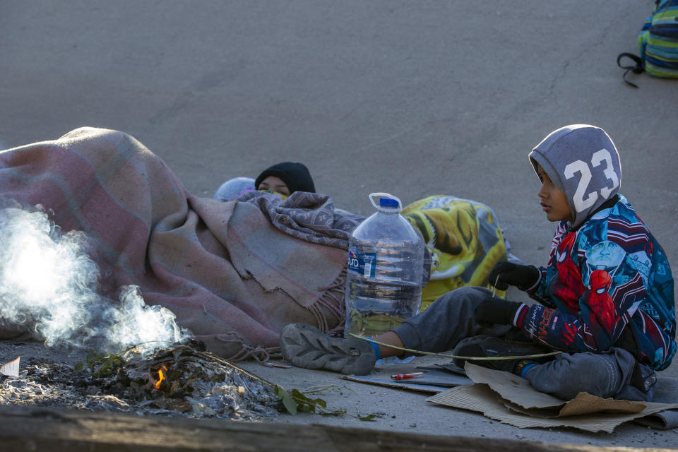 Migrants try to stay warm after spending the night on the southern bank of the Rio Grande in Ciudad Juarez, Mexico, on Wednesday, Dec. 21, 2022. (AP Photo/Andres Leighton)