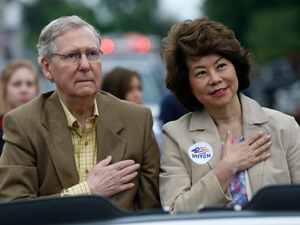 Mitch McConnell and Elaine Chao hold their hands over their hearts as the national anthem plays at a campaign event in 2014