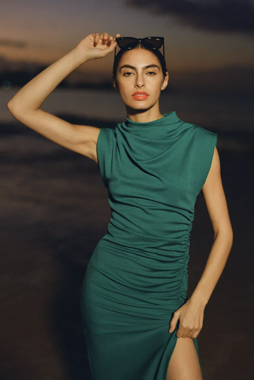 model wearing green The Maya Ruched Cowl-Neck Dress against sunset on beach (photo via Anthropologie)