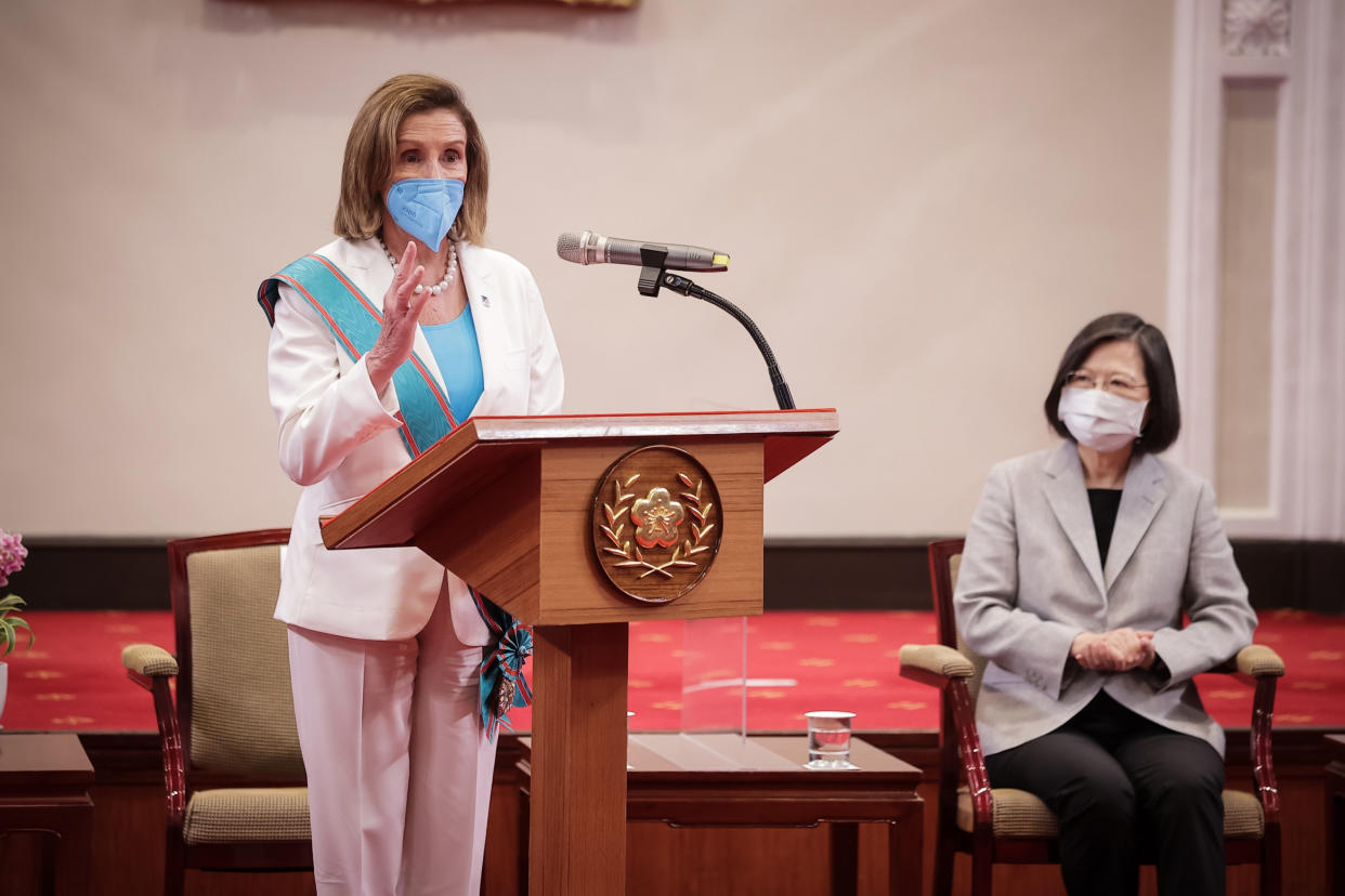 Nancy Pelosi stands at a podium with a microphone next to Taiwan President Tsai Ing-wen, seated. Both wear face masks.