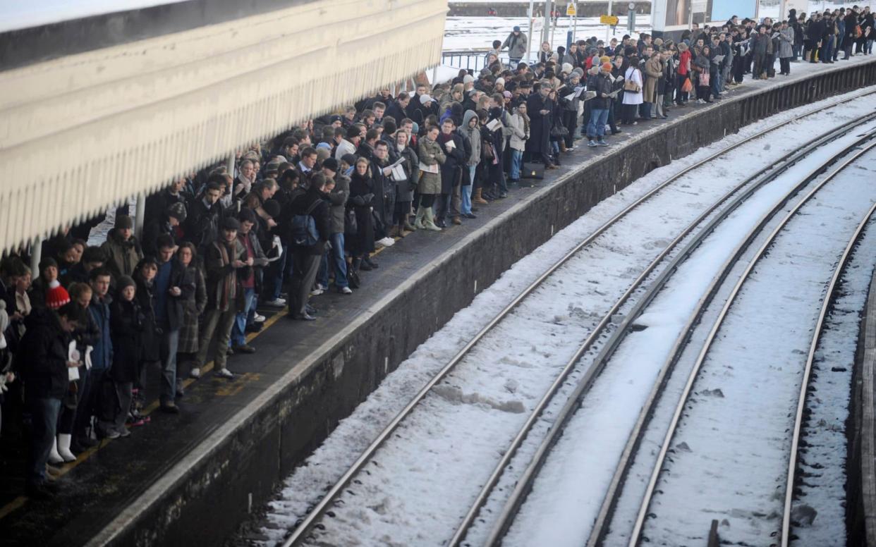 Commuters wait for a train in a snow-covered Clapham Junction  - Reuters