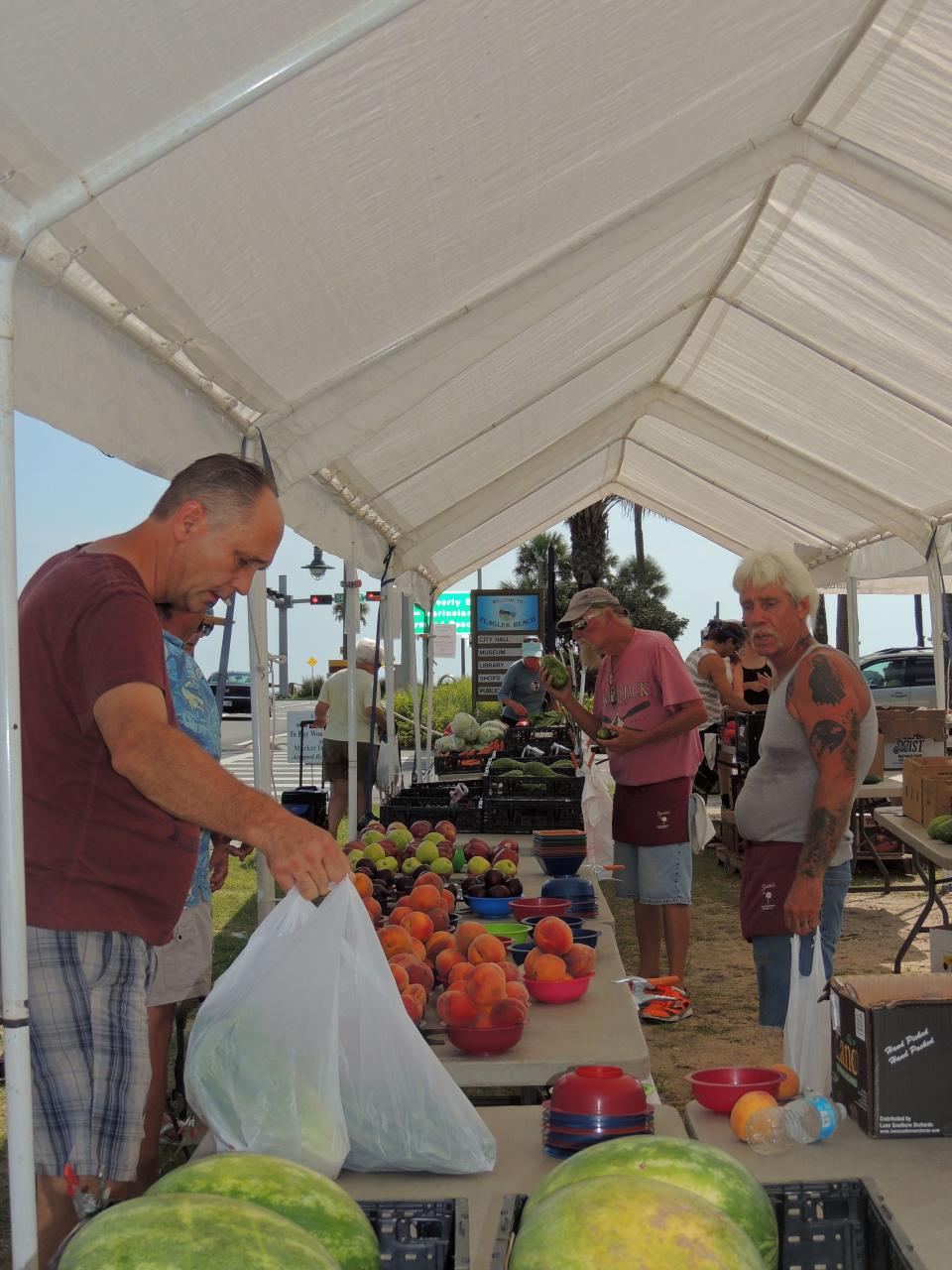 Visitors check out fresh peaches at the Flagler Beach Farmers Market, a weekly fixture in Flagler Beach.