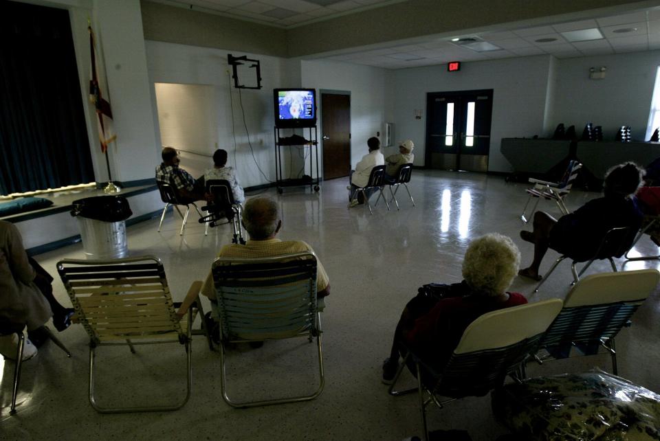 Residents watch the weather on a television at Dr. N.E. Roberts Elementary in North Lakeland as they wait for Hurricane Charley to arrive in in 2004.