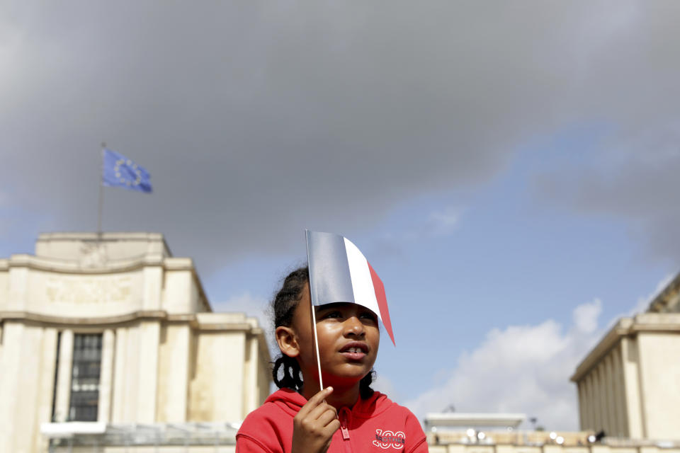 A small girl holds a French flag as she joins others in the Olympics fan zone at the Trocadero in Paris, Sunday, Aug. 8, 2021. A giant flag will be unfurled on the Eiffel Tower in Paris Sunday as part of the handover ceremony of Tokyo 2020 to Paris 2024, as Paris will be the next Summer Games host in 2024. The passing of the hosting baton will be split between the Olympic Stadium in Tokyo and a public party and concert in Paris. (AP Photo/Adrienne Surprenant)