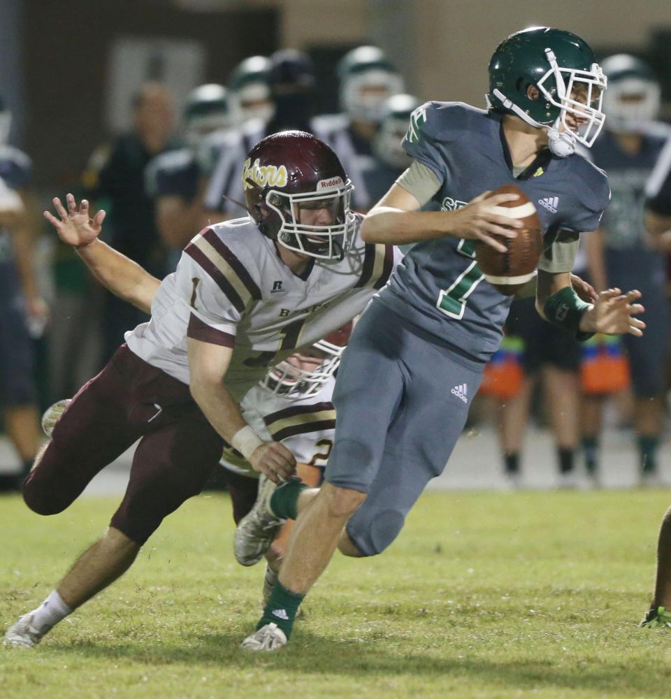 Seahawks backup QB Carson Hawk is chased down by Baker’s Brandon Moss during their game at South Walton High school Friday.