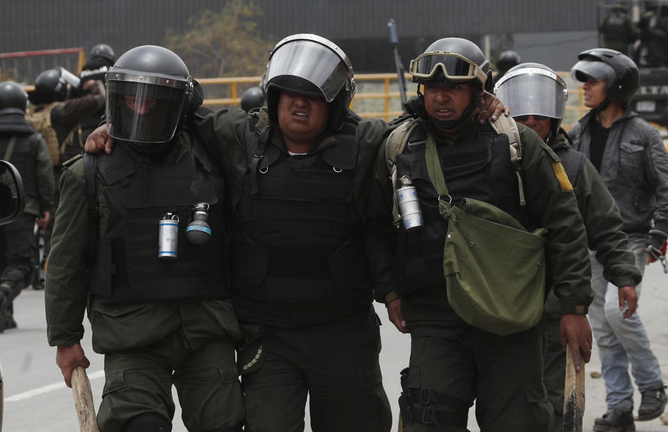 Police help an injured colleague during clashes with supporters of former President Evo Morales in La Paz, Bolivia, Monday, Nov. 11, 2019. Morales' Nov. 10 resignation, under mounting pressure from the military and the public after his re-election victory triggered weeks of fraud allegations and deadly demonstrations, leaves a power vacuum and a country torn by protests against and for his government. (AP Photo/Juan Karita)