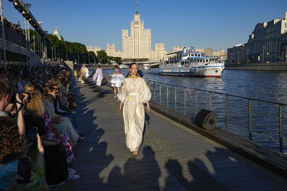 Models display a collection by Russian designer Alena Akhmadullina on Moskvoretskaya embankment during the Fashion Week at Zaryadye Park near Red Square with a Stalin's type skyscraper in the background in Moscow, Russia, Thursday, June 23, 2022. Chic and adventurous models and couturiers have been spread all over the Russian capital for Moscow Fashion Week, flaunting their designs in venues ranging from a sprawling Stalin-era propaganda exposition to a large park near the Kremlin admired for its innovative features. More than 100 shows are being held during the week that began Monday as well as scores of speakers who are noted names in the Russian fashion industry. (AP Photo/Alexander Zemlianichenko)