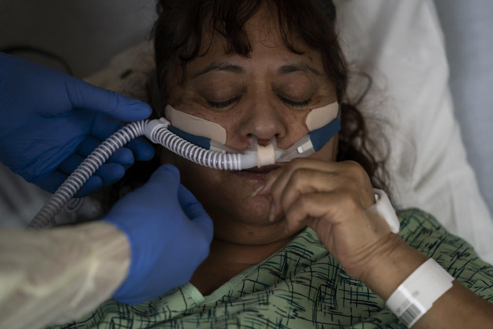 Respiratory therapist Frans Oudenaar replaces an oxygen tube for Linda Calderon, 71, in a COVID-19 unit at Providence Holy Cross Medical Center in Los Angeles, Tuesday, Dec. 14, 2021. At the medical center, just 17 coronavirus patients were being treated there Friday, a small fraction of the hospital's worst stretch. Nurse manager Edgar Ramirez said his co-workers are weary but better prepared if a wave hits. (AP Photo/Jae C. Hong)