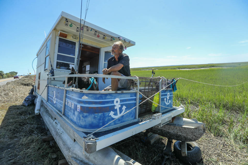 Huck and his dog Creed are still living on a pontoon boat that is currently stranded on the shoulder of US 80 after high winds and tides from Hurricane Helene pushed his boat onto the shore from the Back River.