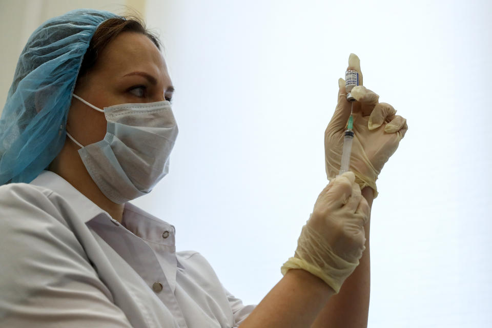 A Russian medical worker prepares a shot of Russia's Sputnik V coronavirus vaccine in Moscow, Russia, Saturday, Dec. 5, 2020. Thousands of doctors, teachers and others in high-risk groups have signed up for COVID-19 vaccinations in Moscow starting Saturday, a precursor to a sweeping Russia-wide immunization effort. (AP Photo/Pavel Golovkin)