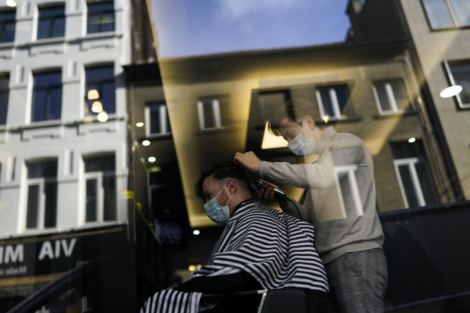 FILE - In this Tuesday, Feb. 16, 2021 file photo, a client, wearing a face mask to prevent against the spread of coronavirus, gets his hair styled at a hairdresser's shop in Brussels. The government on Monday, Feb. 22, 2021 presented scientific projections of the spread of the COVID-19 pandemic in Belgium, indicating it would be very risky to extensively loosen the current restrictions over the coming weeks. (AP Photo/Francisco Seco, File)