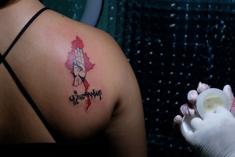 Woman displays a tattoo with a three-finger salute over a map of Myanmar in Yangon
