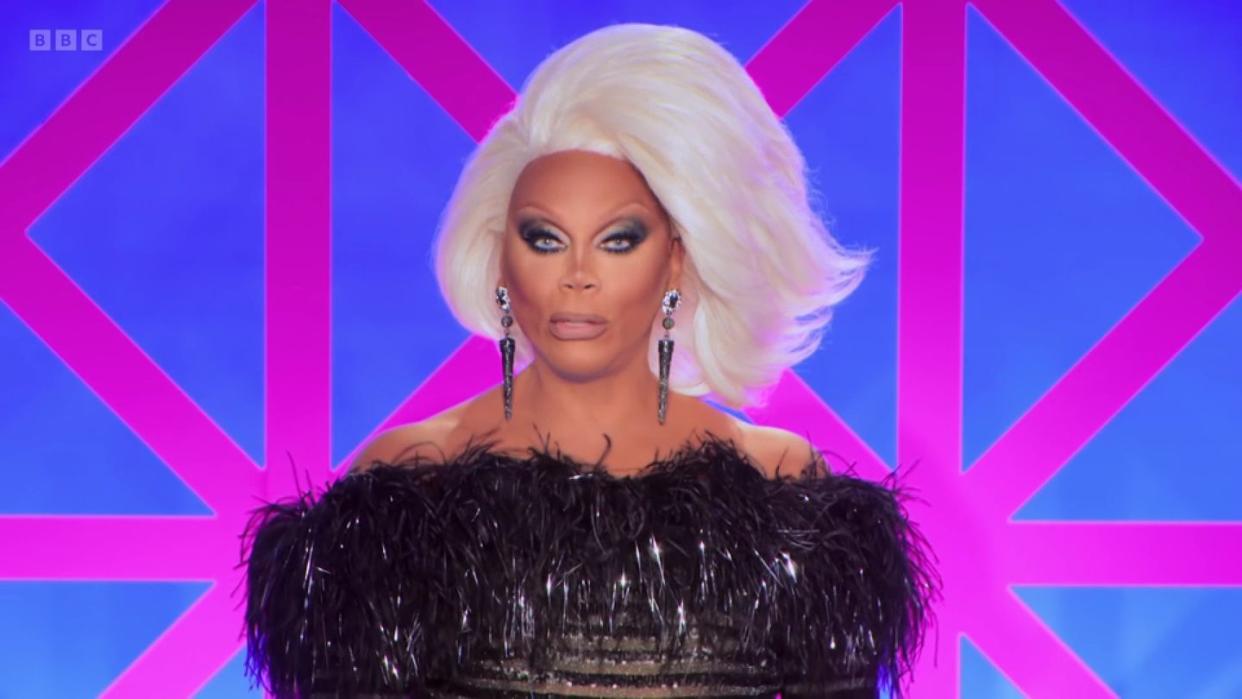 rupaul in drag race uk s5 episode 5, with a short white wig and a black outfit