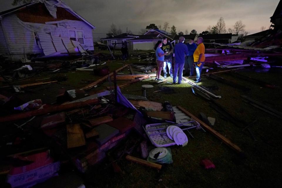 Christine Wiecek, left, and her husband Robert Patchus, second left, talk to neighbors amongst debris of their damaged homes after a tornado struck the area in Arabi, Louisiana on Tuesday (AP)