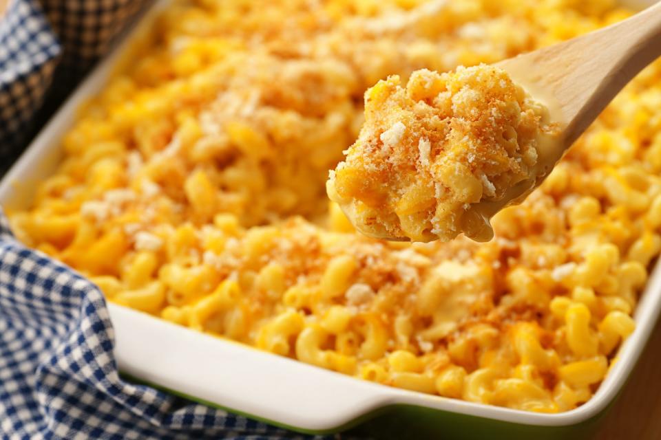 A spoonfull of homestyle baked macaroni and cheese with crispy breadcrumbs and shredded cheddar. Sharp focus on the contents of the spoon.