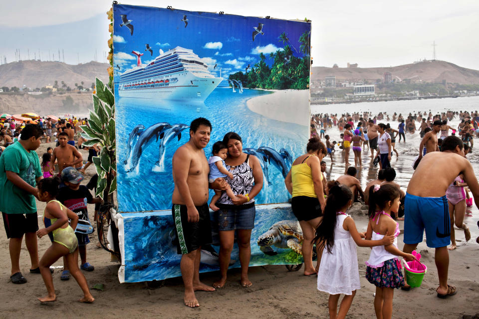 In this March 3, 2013 photo, Karina Alvarado and David Enriquez pose for a picture with their daughter at Agua Dulce beach in Lima, Peru. For five Peruvian soles or about two U.S. dollars beachgoers can pose for a photo to record their day at the beach, in front of backdrops of their choice that include forest landscapes, exotic beach scenes or atop horses. (AP Photo/Rodrigo Abd)