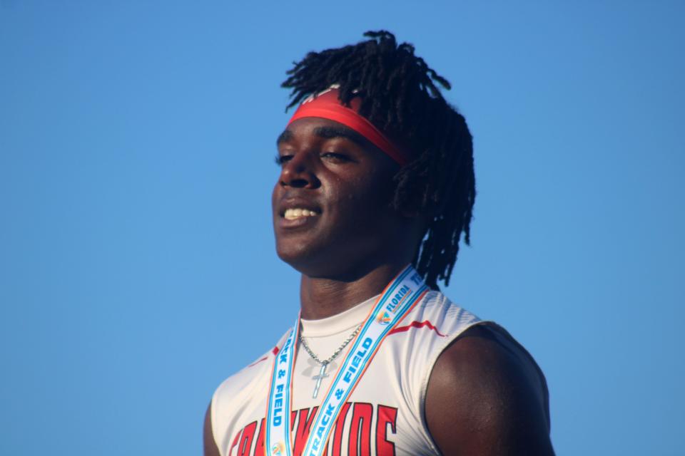 Christian Miller of Creekside smiles on the podium after receiving his medal for winning the boys 100-meter dash.