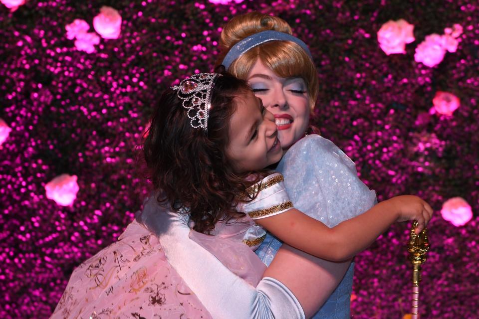 Cinderella wraps her arms around a child at the Once Upon a Wish Party.