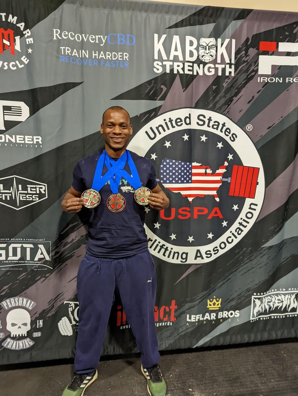 Portsmouth resident Dele Atoro shows off a few medals from a United States Powerlifting Association competition.