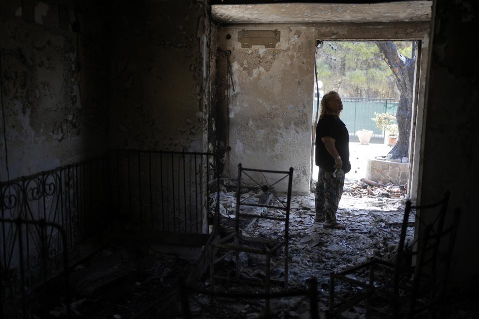 Retiree Chrysoula Renieri visits her burned out home in Loutraki, about 82 kilometres (51 miles) west of Athens, Greece, Thursday, July 22, 2023. Renieri, 72, was among dozens of people who lost their home in the area as wildfires tore through hillside scrub and forests outside Athens. (AP Photo/Thanassis Stavrakis)