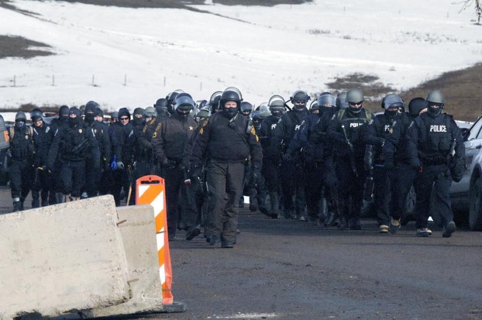 Several dozen law enforcement personal march south on Highway 1806 before assembling above the Oceti Sakowin camp to begin the final sweep of Dakota Access oil pipeline of the camp and arrests of protesters Thursday, Feb. 23, 2017, near Cannon Ball, N.D. (Mike McCleary/The Bismarck Tribune via AP, Pool)