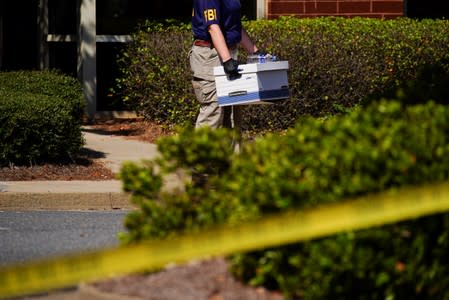 An FBI agent carries a box out of Alpha Medical Consulting as federal agents execute a search warrant in Lawrenceville