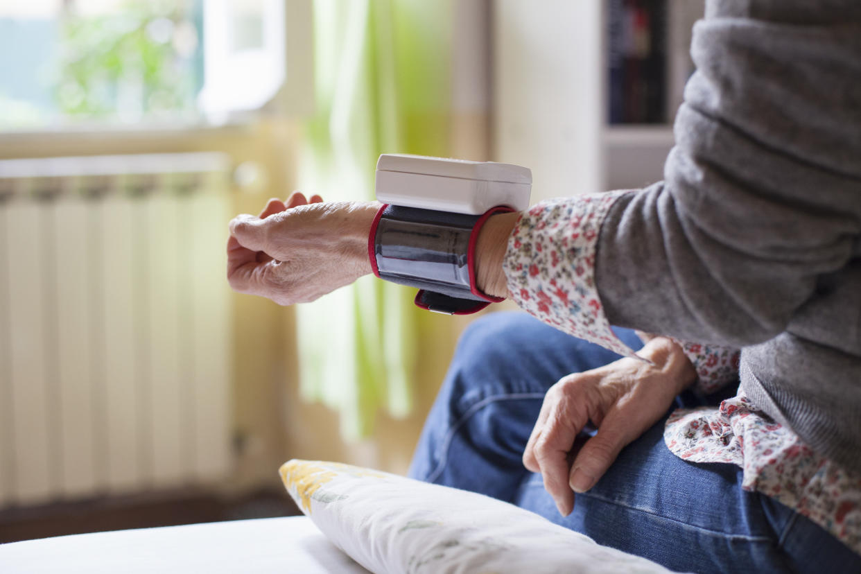 Senior woman sitting on bed, measuring her blood pressure. (Photo: Getty Images)