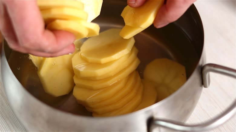 Raw potato slices submerged in pot 